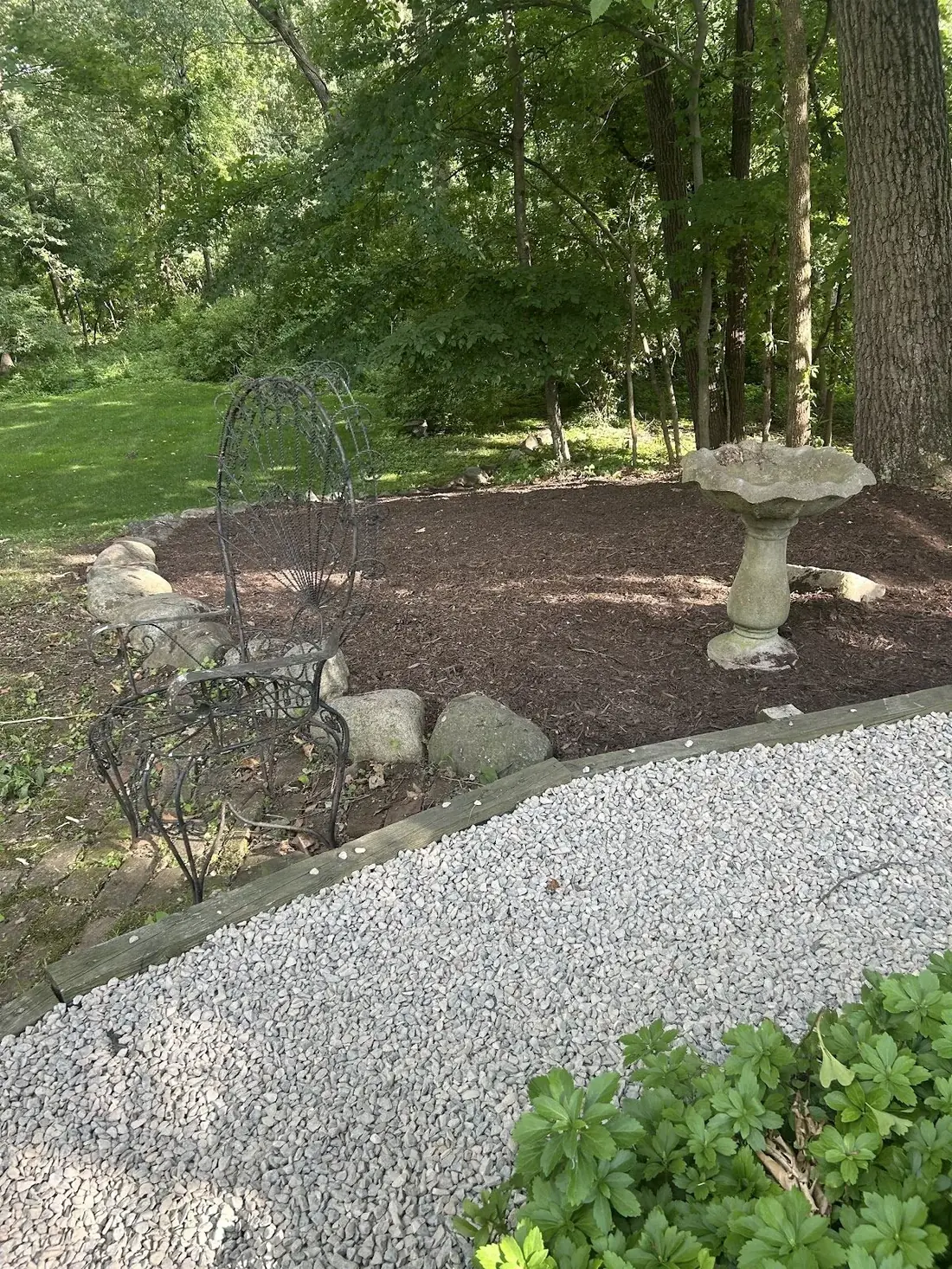 Fresh mulch bed with new plantings and a stone birdbath installed by AJC Landscaping in Oakland County, MI